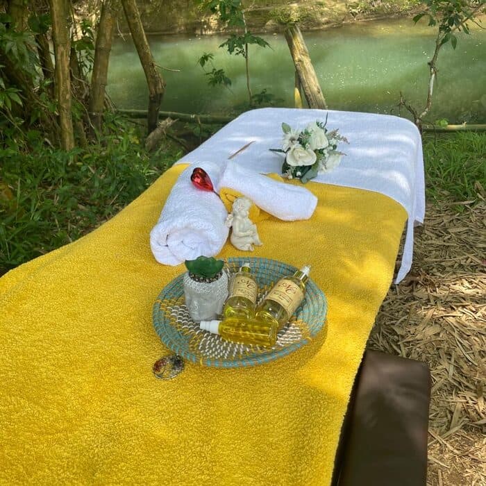 Table de massage et huiles au bord d'une rivière tropicale